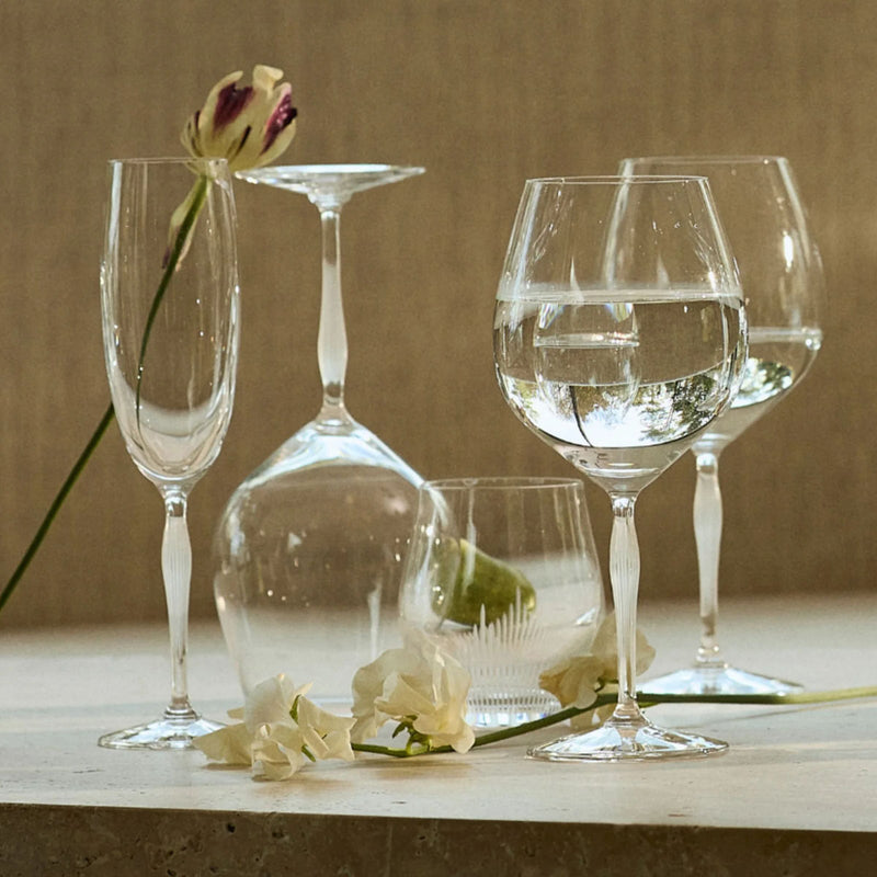 Clear stemmed wine glass with rounded bowl on table with decanter and flowers