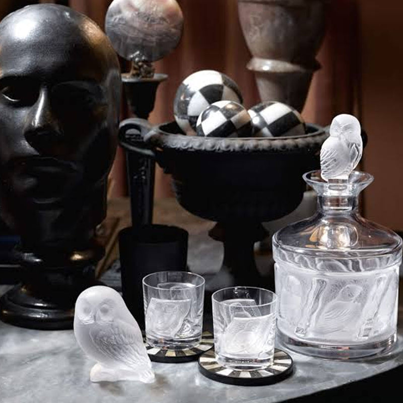 White glass owl figurine with detailed wings near tumblers and a decanter
