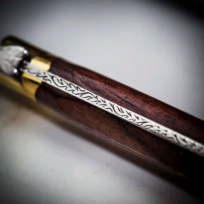 Carving knife handle close-up with rosewood, gold ferrule, and engraved metal