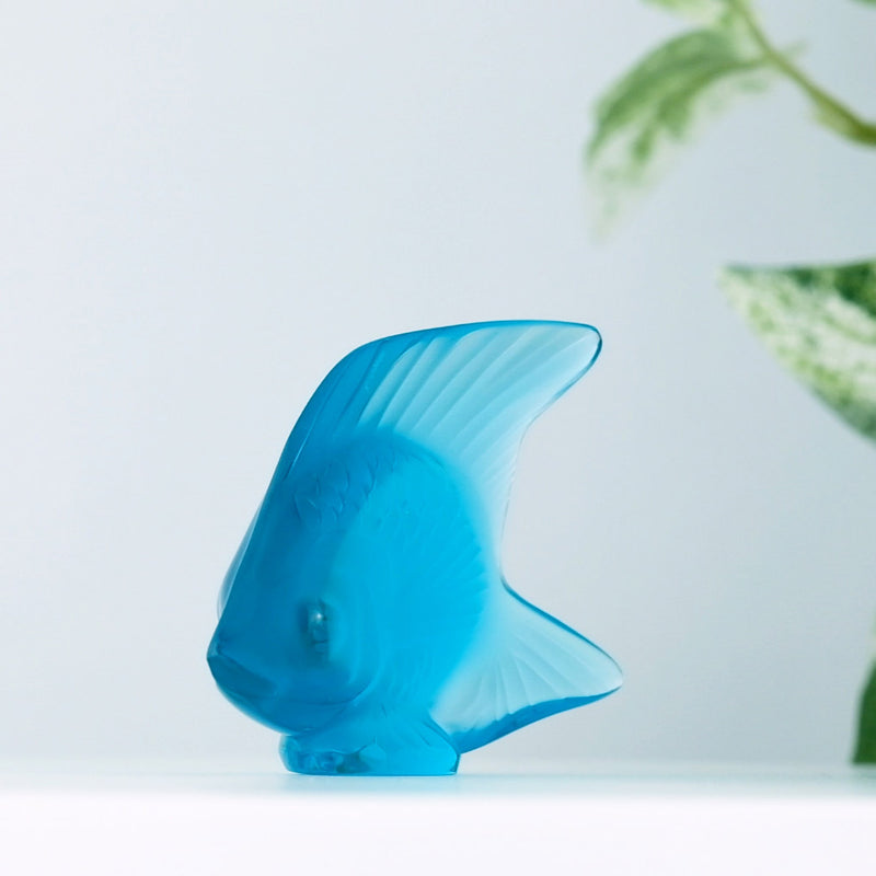 Lalique Light Turquoise Fish with a plant in the background