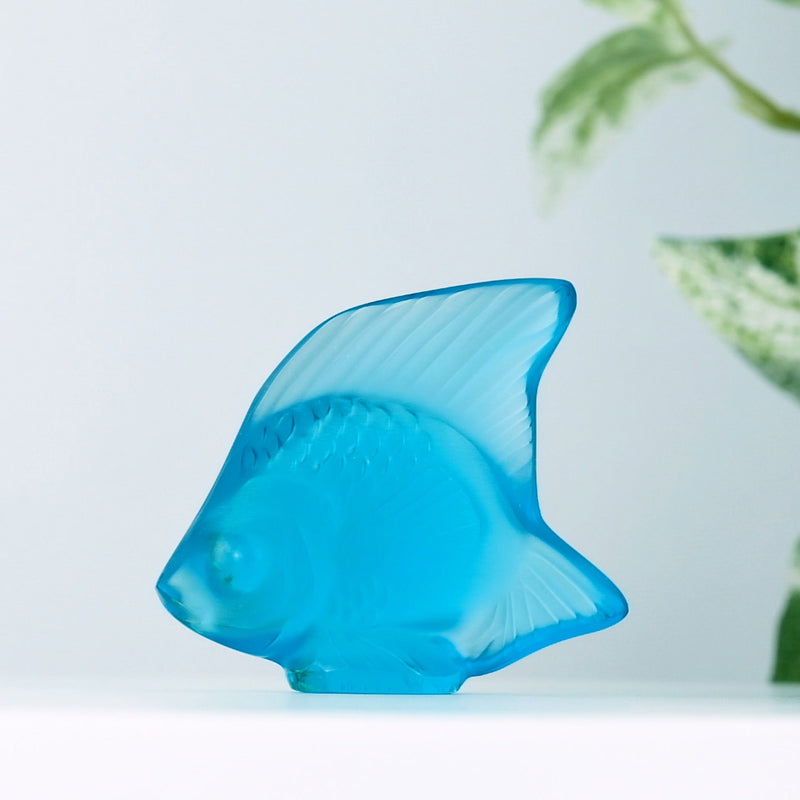 Lalique Light Turquoise Fish with a plant in the background
