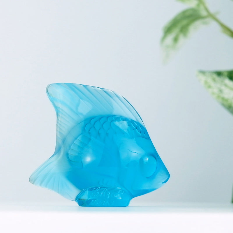 Lalique Light Turquoise Fish with a plant in the background